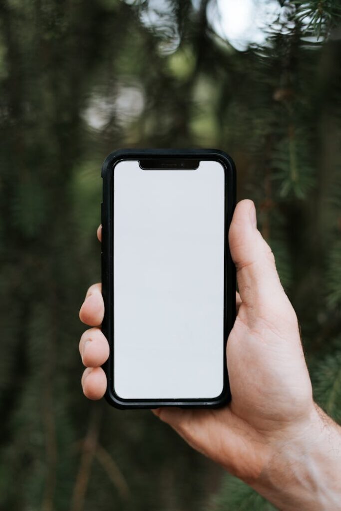 An outdoor shot of a hand holding a smartphone with a blank screen for mockup purposes.
